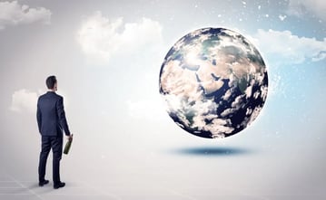 Businessman standing with his back with objects in his hand and looking at the globe, courtesy of NASA