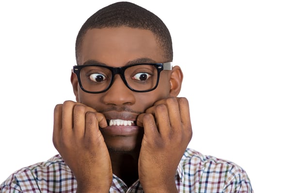 Closeup portrait of young nerdy, unhappy, scared man, student with big glasses biting nails, looking away with a craving for something, anxious, worried, isolated on white background. Face expression