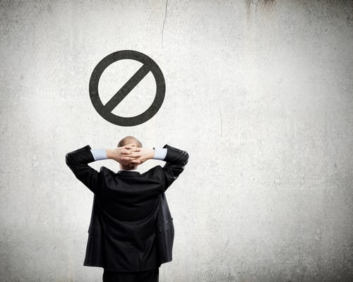 Rear view of thoughtful businessman looking at prohibition sign